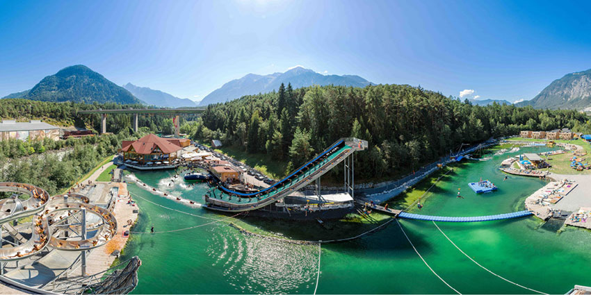 Türkisgrüner Schwimmsee mit Wasserrutsche, Blob und weiteren Sportanlagen