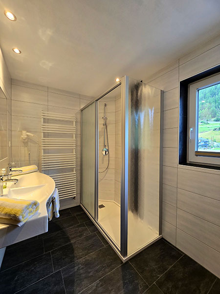 Geräumiges Badezimmer mit Doppelwaschbecken, Fön, großer Duschkabine und Fenster mit schönem Ausblick