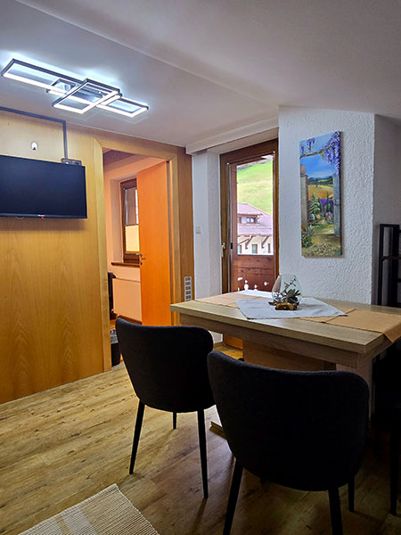 Essbereich der Küche mit TV an der Wand und Sicht auf Balkontüre